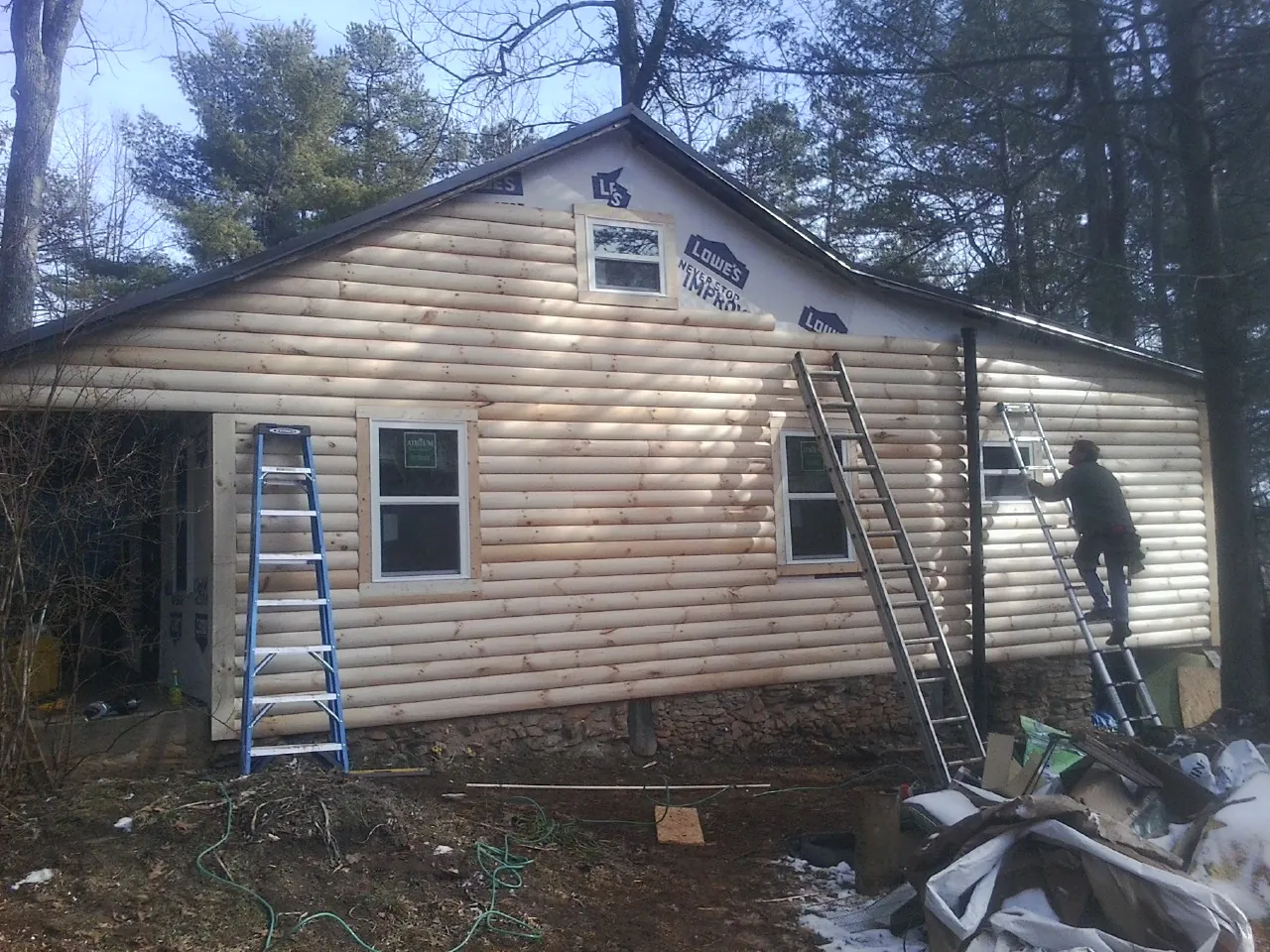 Ladders set against fresh log siding during an exterior remodel in Glen Cove