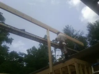 Carpenter setting a ridge beam over a new addition frame — Ice Dam Removal by Roofing Brothers in Glen Cove