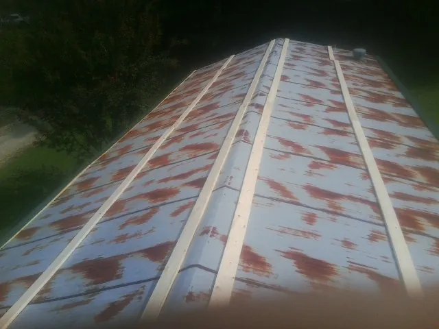 Rusted metal roof panels with new wood purlins before replacement — Storm Damage Roof Repair in Glen Cove by Roofing Brothers