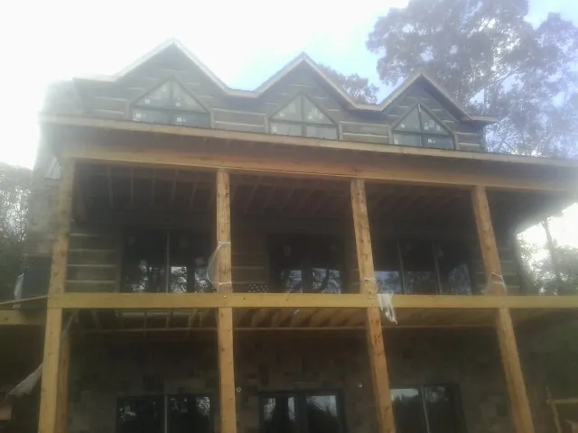 Dormers and porch framing on a large log home under construction — Roof Coating work by our crew in Glen Cove
