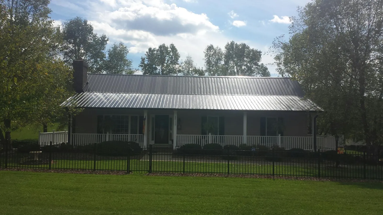 Gray metal roof on a brick ranch with a full width front porch — Gutter Guard Installation work by our crew in Glen Cove