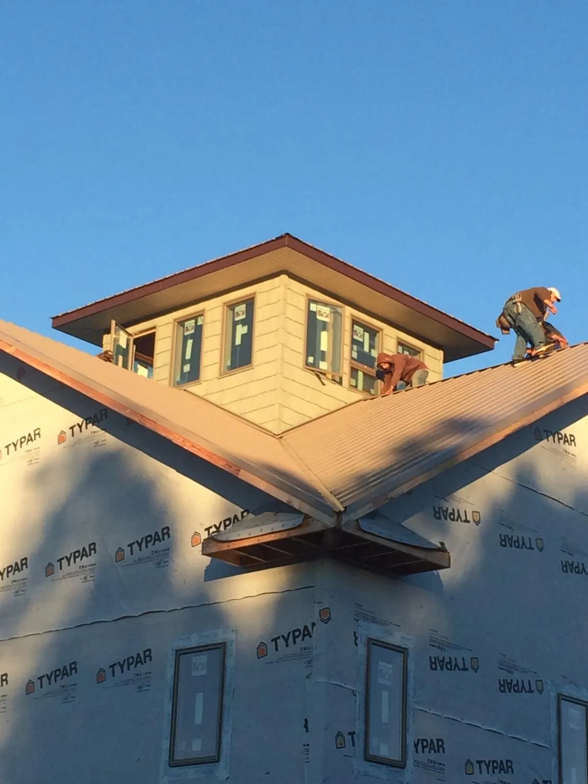 Roofers working around a rooftop cupola on a new metal roof at sunset — Roof Waterproofing in Glen Cove by Roofing Brothers